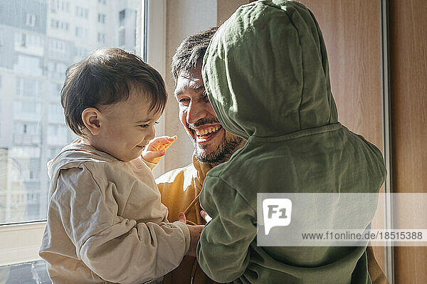 Glücklicher Vater genießt es mit seinen Söhnen  die zu Hause Kapuzenpullis tragen