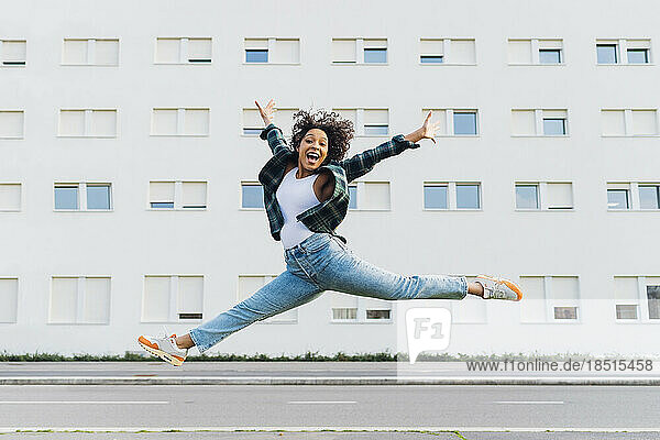 Cheerful woman jumping in front of building