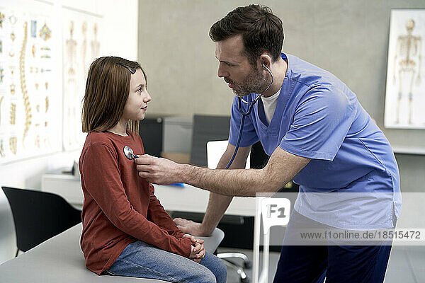 Mature doctor examining girl in clinic