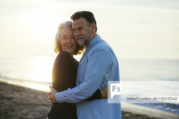 Mature man hugging woman at sunrise