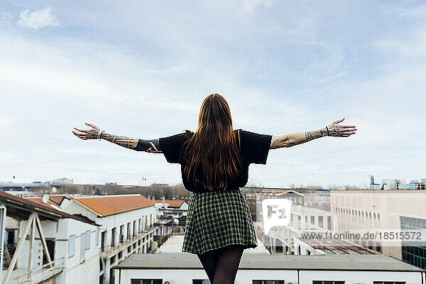 Woman with arms outstretched standing on building terrace