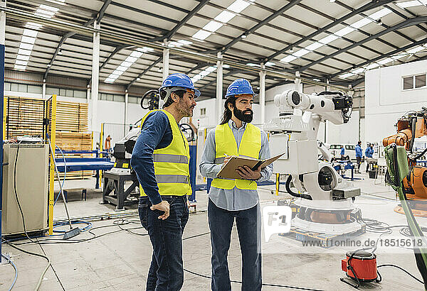 Engineers wearing hardhat examining machines in industry