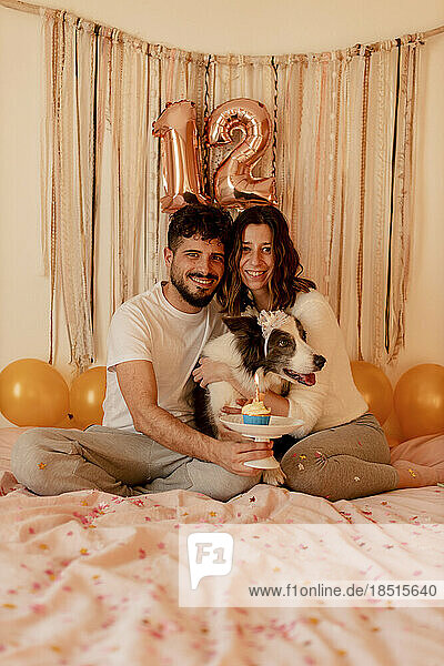 Happy man and woman celebrating border collie dog's birthday at home