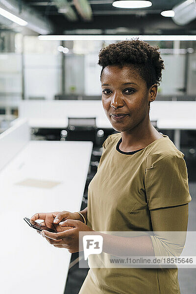Businesswoman holding mobile phone in office