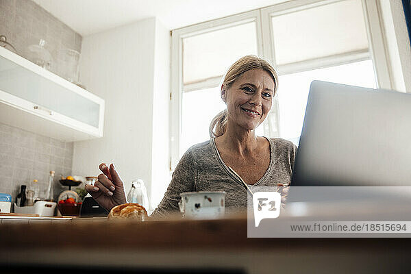 Smiling freelancer with laptop on table at home office