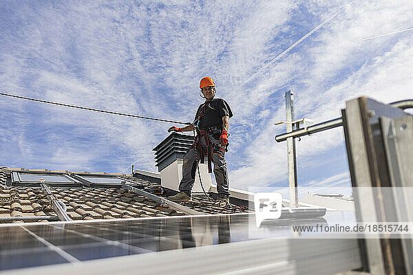 Engineer wearing safety harness standing on rooftop
