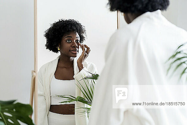 Woman applying moisturizer under eyes