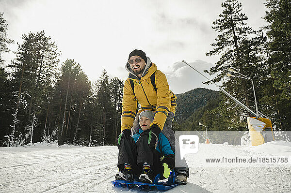 Glücklicher Vater und Sohn genießen das Rodeln im Schnee