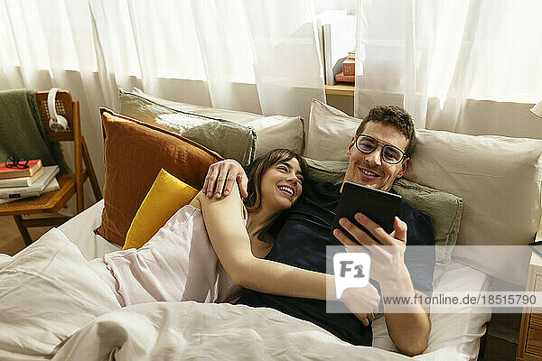 Couple looking at tablet PC lying in bed at home