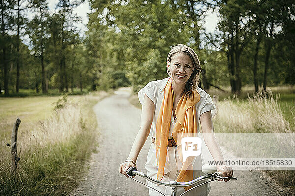 Glückliche Frau fährt Fahrrad auf unbefestigter Straße