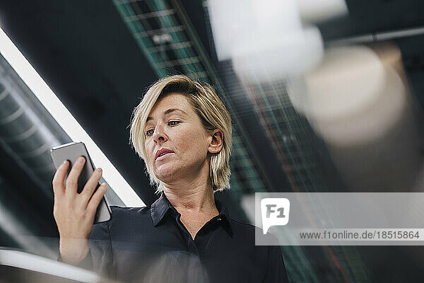 Businesswoman looking at smart phone in office