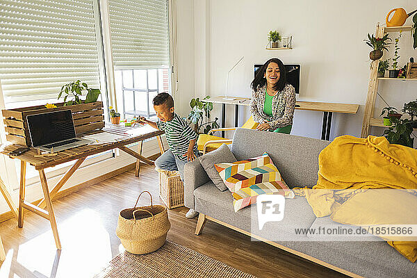 Cheerful boy playing with mother in living room at home