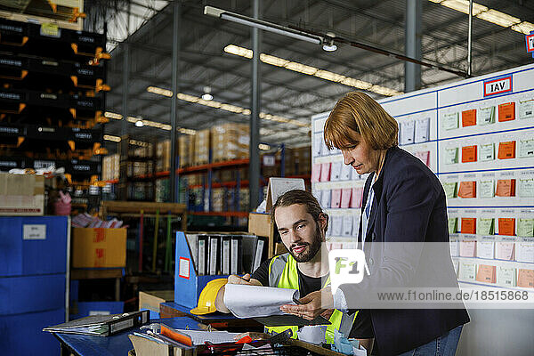 Manager showing checklist to colleague at warehouse