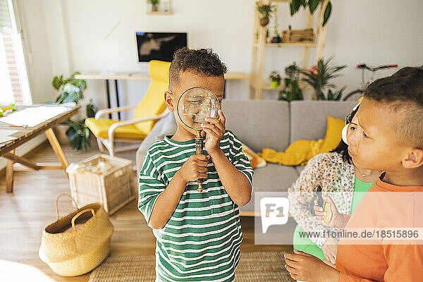 Boy looking through magnifying glass at home