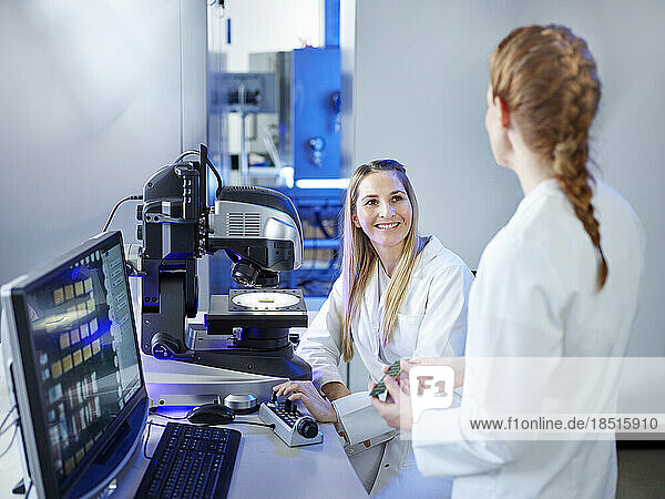 Smiling scientist discussing with technician at E-Laboratory