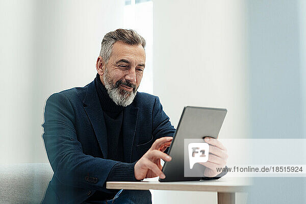 Smiling businessman using tablet PC at desk