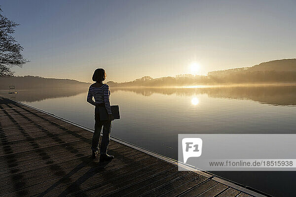 Freelancer standing with laptop looking at lake