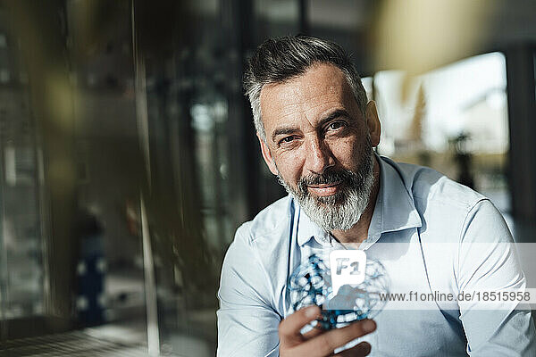 Smiling mature businessman holding electric computer fan