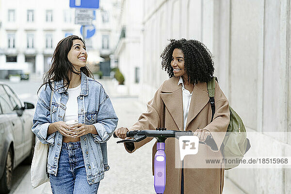 Happy young woman walking with friend by building