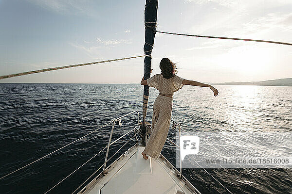 Frau mit erhobenem Arm steht auf einem Segelboot