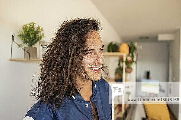 Happy young man with long hair at home