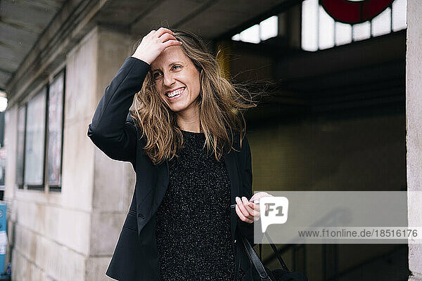 Happy woman with hand in hair holding smart phone