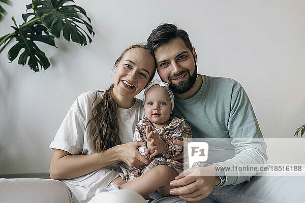 Father and mother with cute daughter in front of wall
