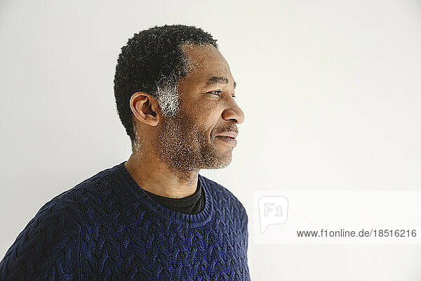Contemplative mature man in front of white wall