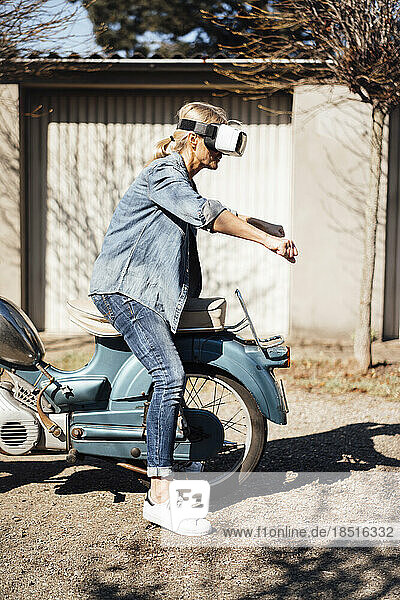 Woman wearing VR glasses gesturing on motorcycle