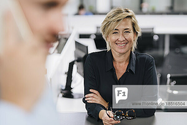 Happy businesswoman holding eyeglasses at office