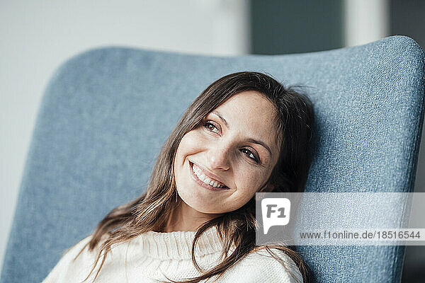 Thoughtful happy woman resting in armchair