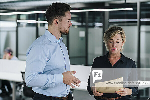Businesswoman reading document by colleague in office