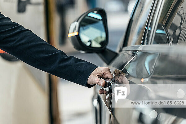 Hand of businessman opening car door