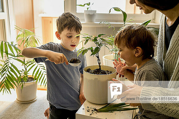 Mother with children taking care of plants at home