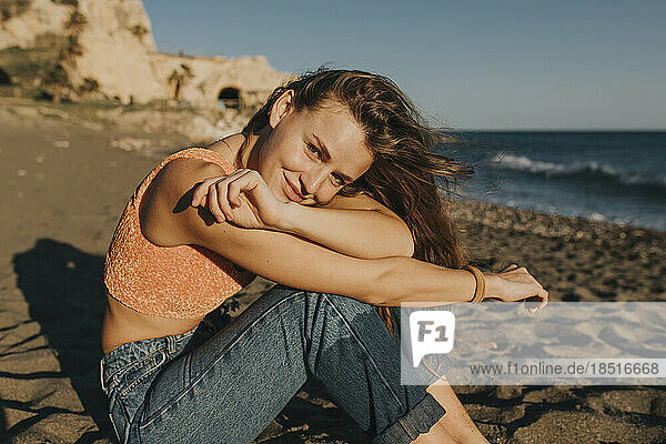 Smiling woman sitting at beach on sunny day