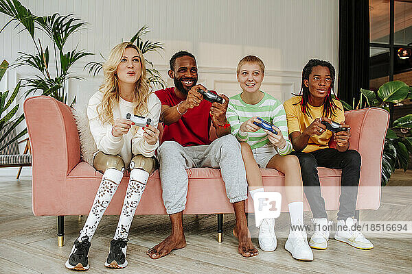 Happy young man with friends playing video game at home