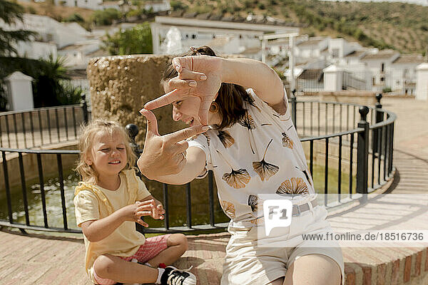 Glückliche Mutter macht an einem sonnigen Tag einen Fingerrahmen mit ihrer Tochter