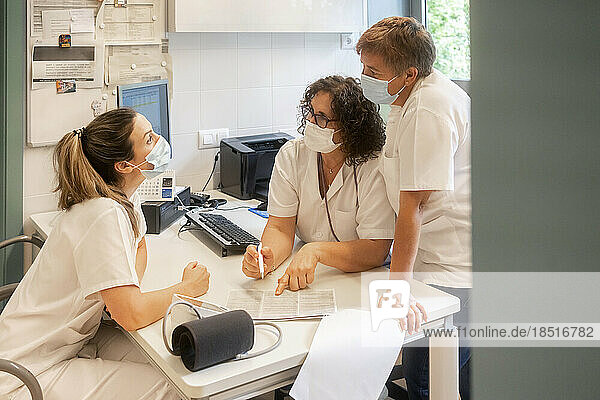 Krankenschwestern mit Schutzmasken diskutieren gemeinsam in der Klinik