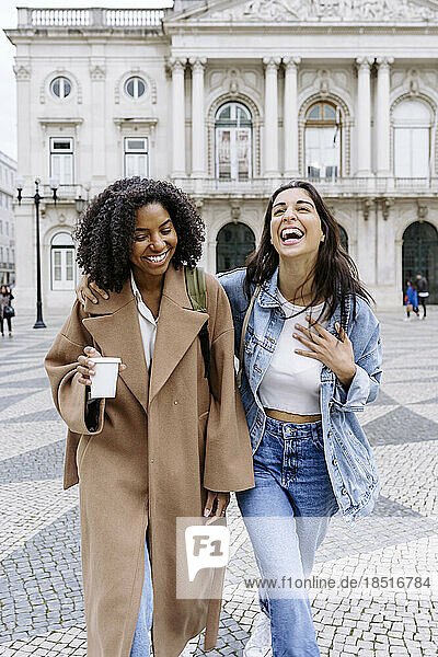 Cheerful woman holding coffee cup enjoying with friend