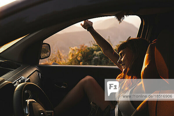 Happy young woman enjoying in car at sunset