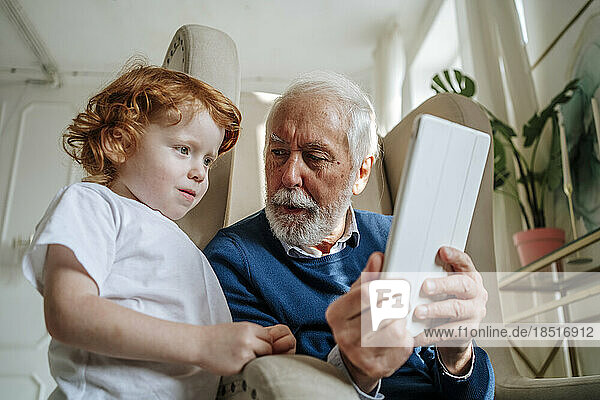 Großvater zeigt Enkel-Tablet-Computer zu Hause