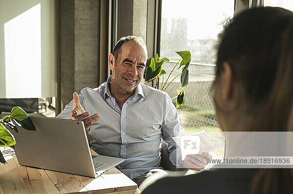 Mature businessman discussing business plan with colleague in office