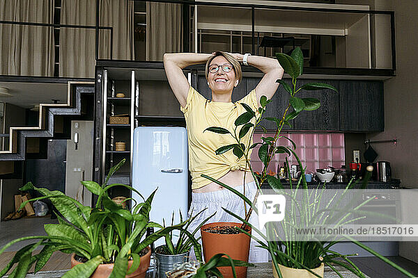 Carefree woman with hands on head standing at home