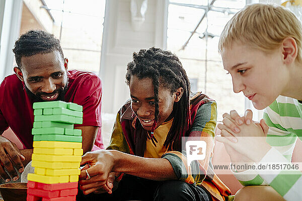 Lächelnde junge Freunde spielen zu Hause Blockentfernungsspiel