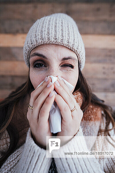 Sick young woman wiping nose with tissue