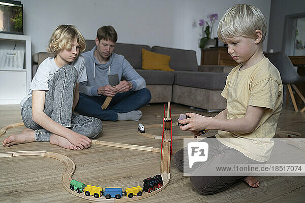 Father and children playing together with toy train at home