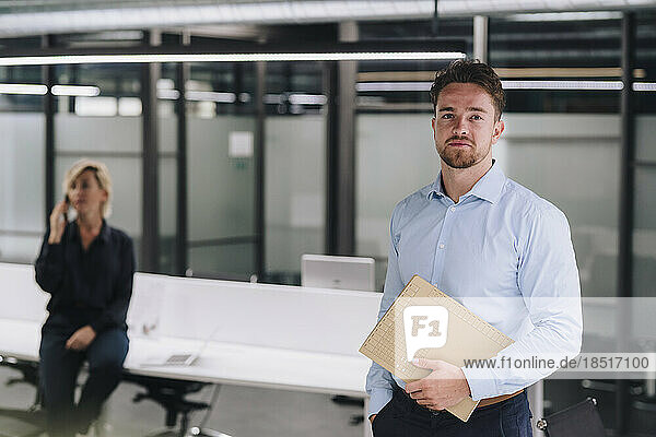 Young businessman holding document with colleague in background