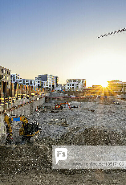 Construction site with backhoes near heap of mud at sunset