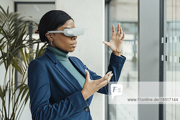 Businesswoman wearing virtual reality headset gesturing at office
