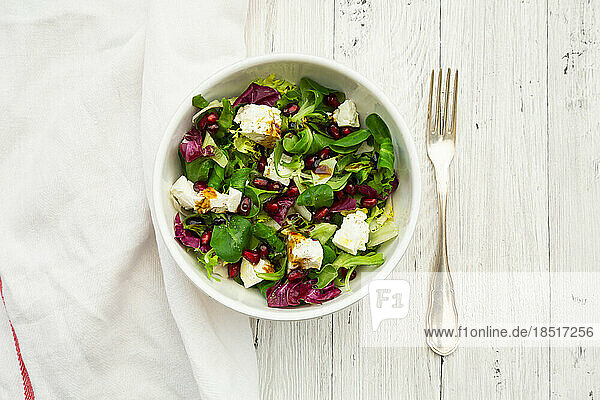 Bowl of mixed vegetarian salad with pomegranate seeds and feta cheese